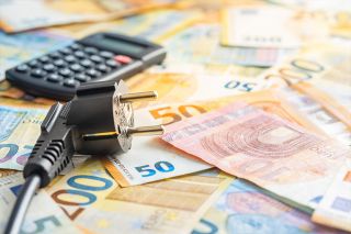 Foto: Taschenrechner, Stromstecker und Bargeld